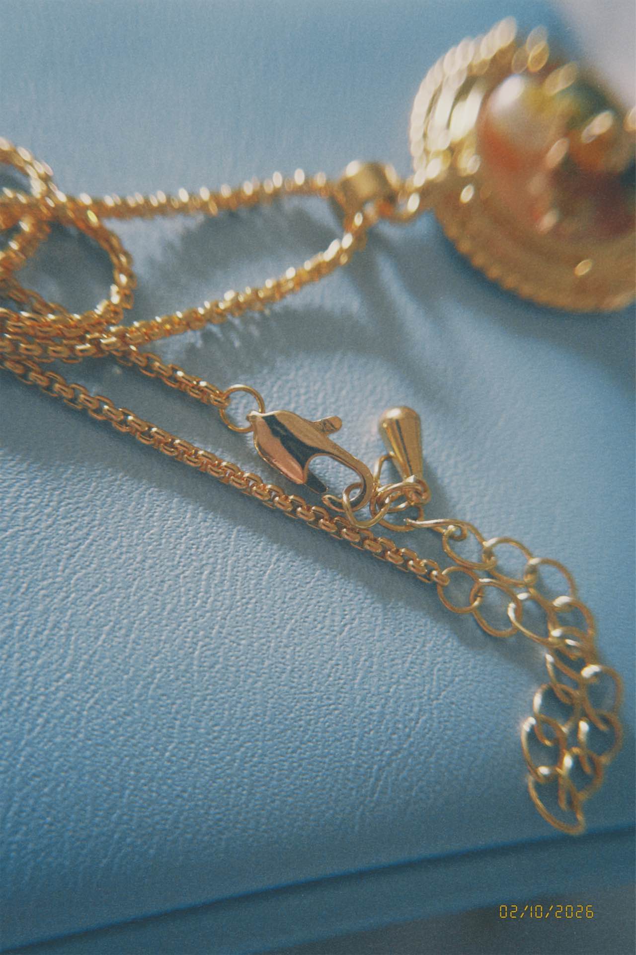 Gold necklace with a pendant on a blue surface
