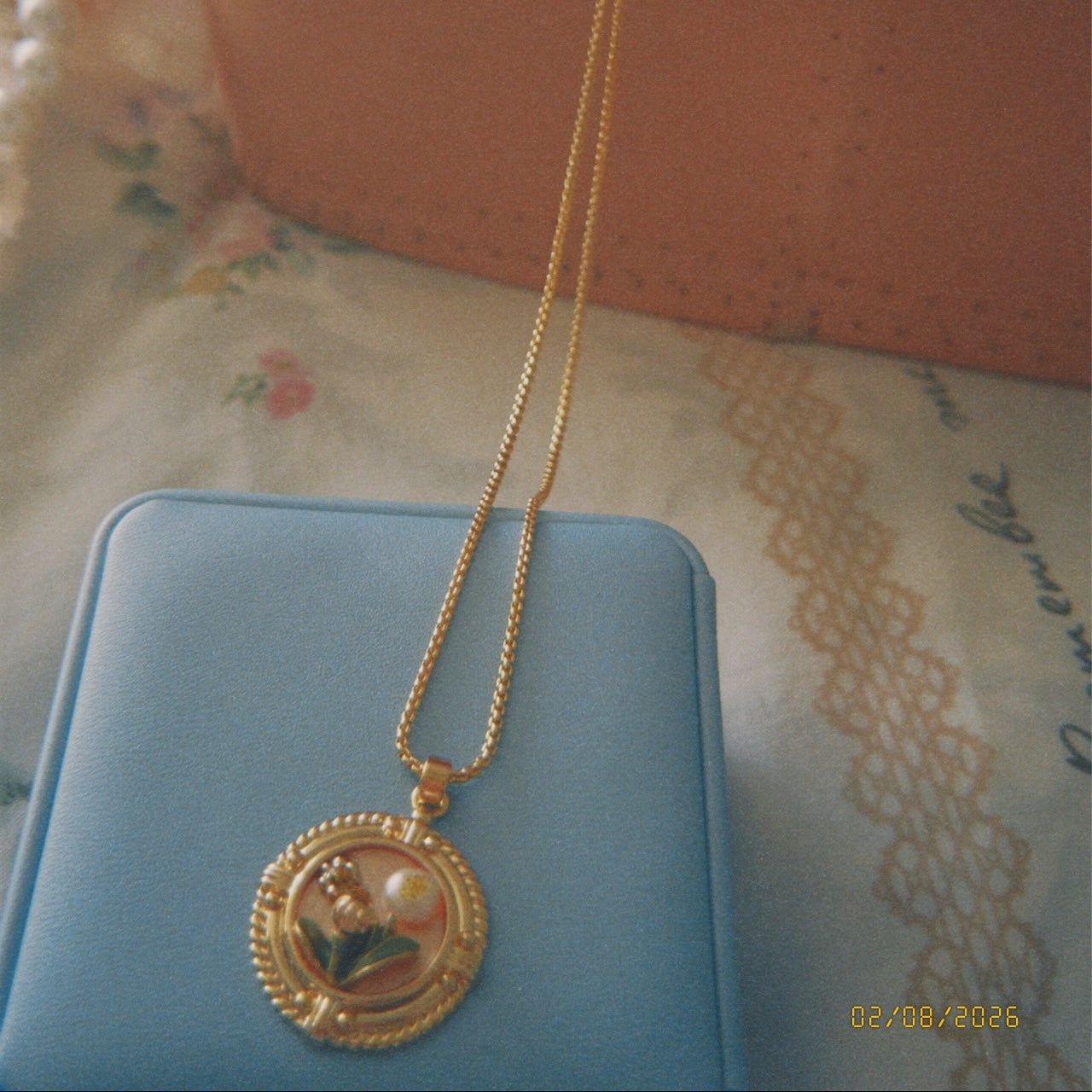 Gold necklace with a pendant on a blue surface