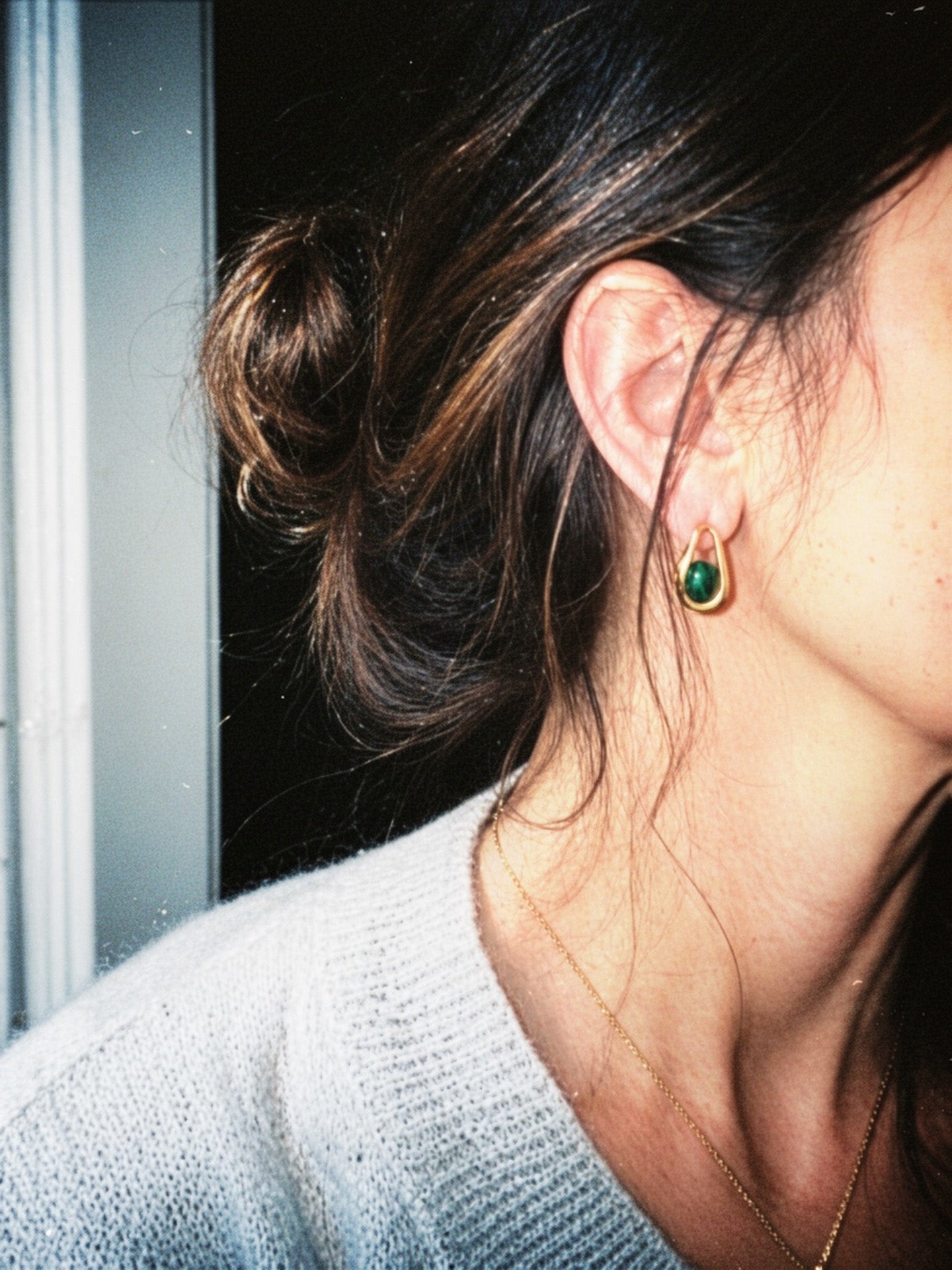 Close-up of a person wearing a green earring with a dark background