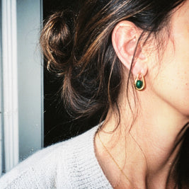 Close-up of a person wearing a green earring with a dark background