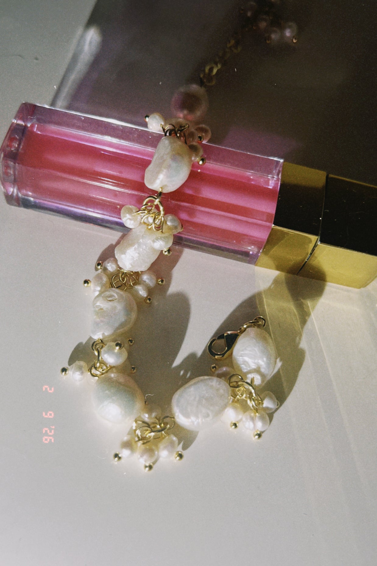 Pearl bracelet with gold accents on a pink lip gloss
