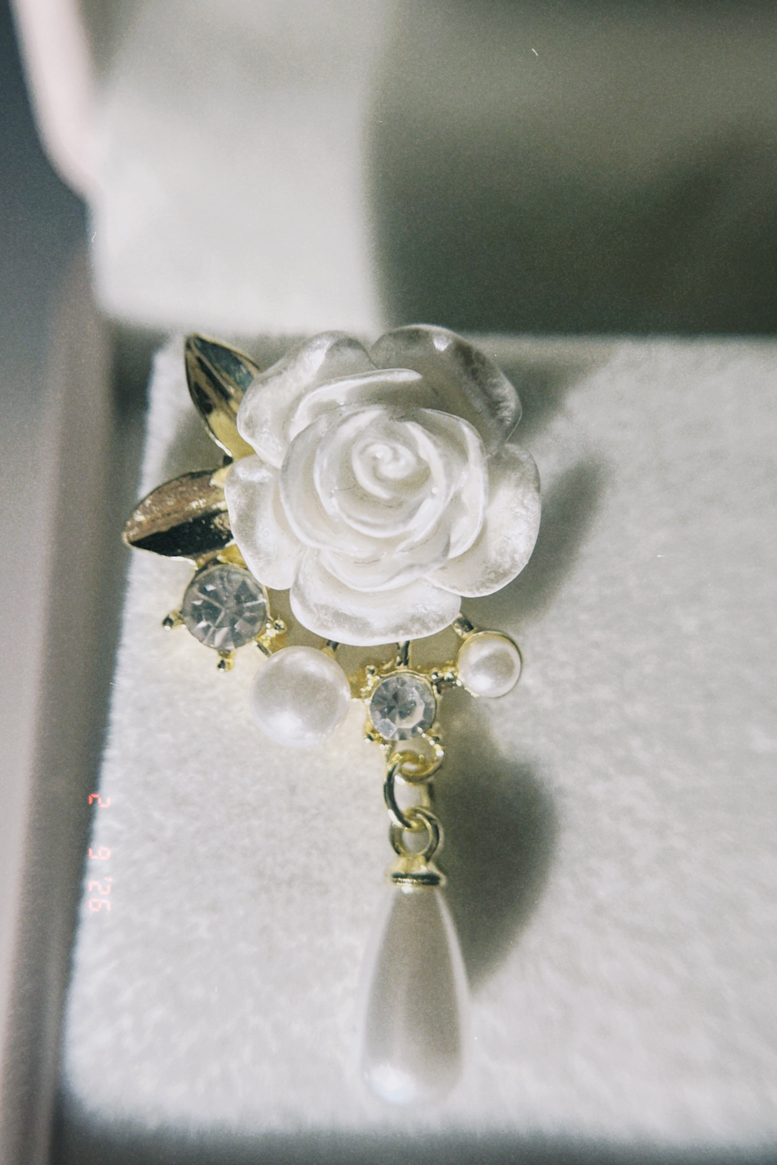 Decorative brooch with white rose design earring on a textured surface