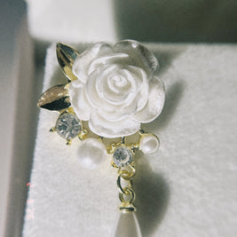 Decorative brooch with white rose design earring on a textured surface