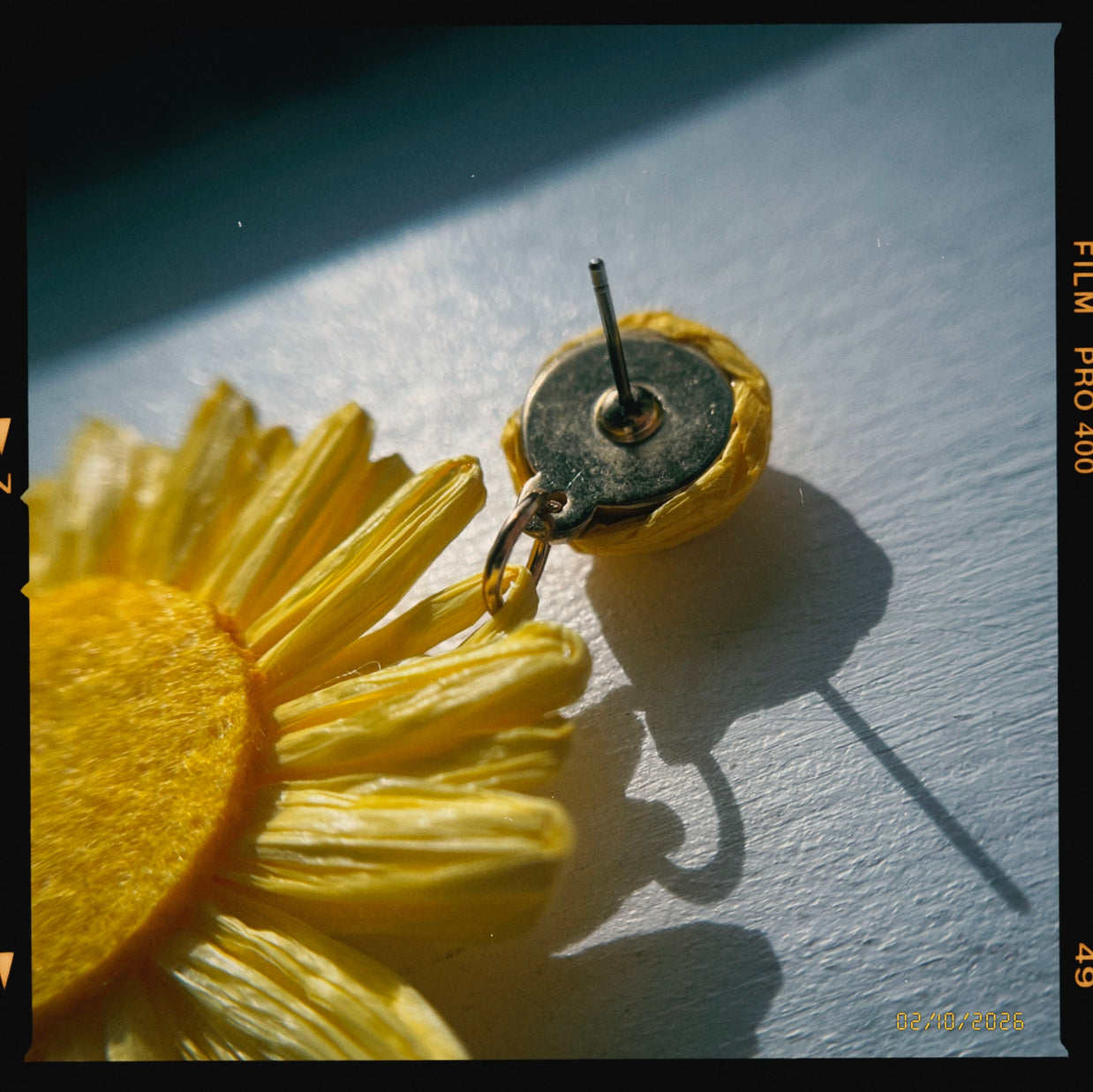 Yellow flower-shaped earring on a light blue background