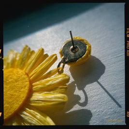 Yellow flower-shaped earring on a light blue background