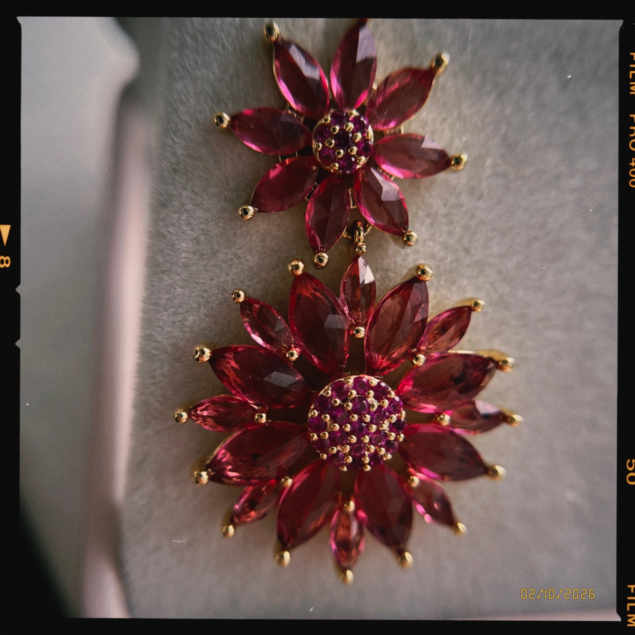 Pair of red floral earrings with gold accents on a neutral background