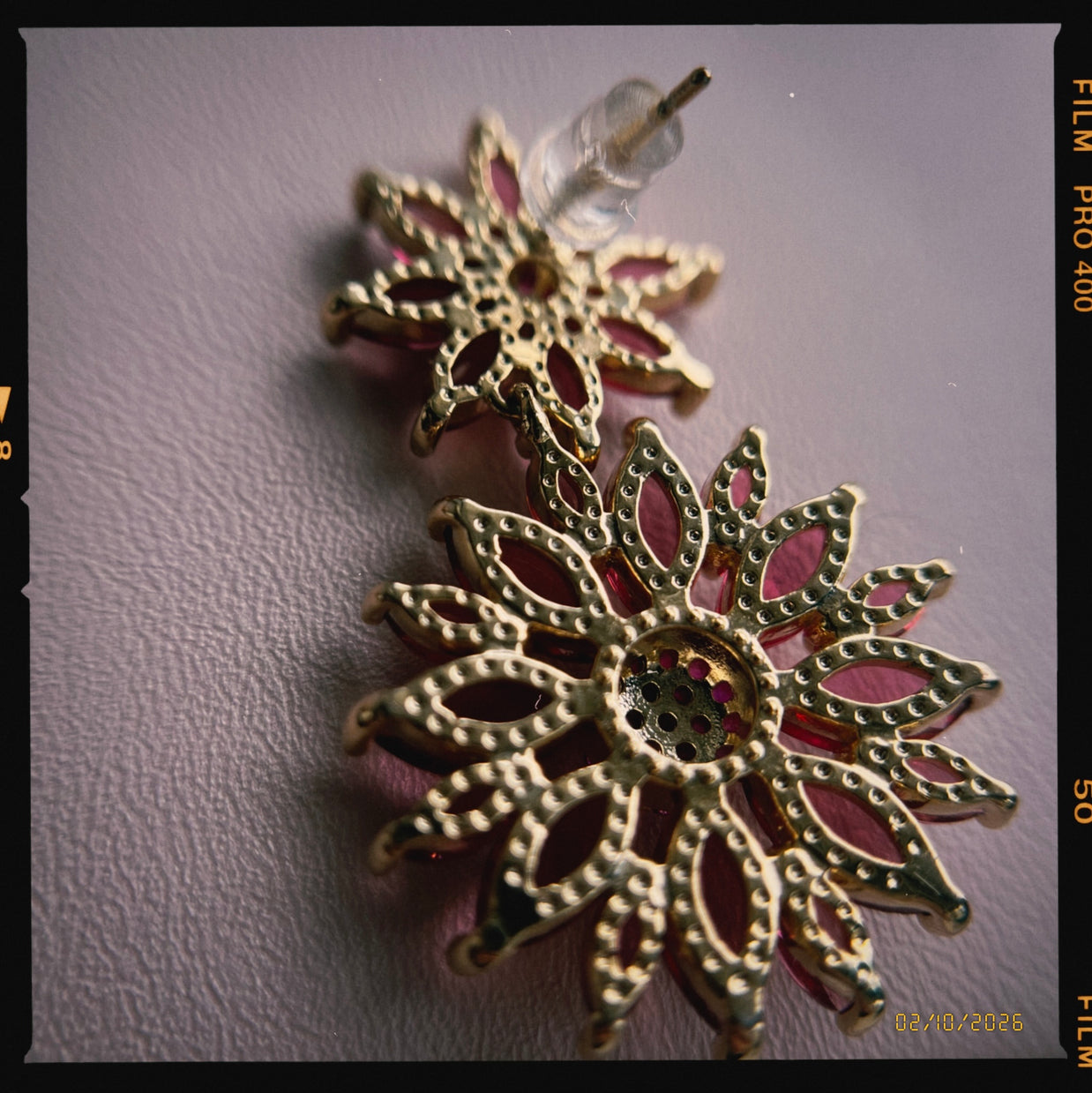 Decorative earrings with gold and red design on a plain background