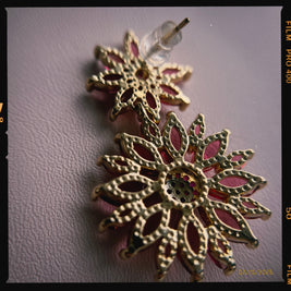 Decorative earrings with gold and red design on a plain background