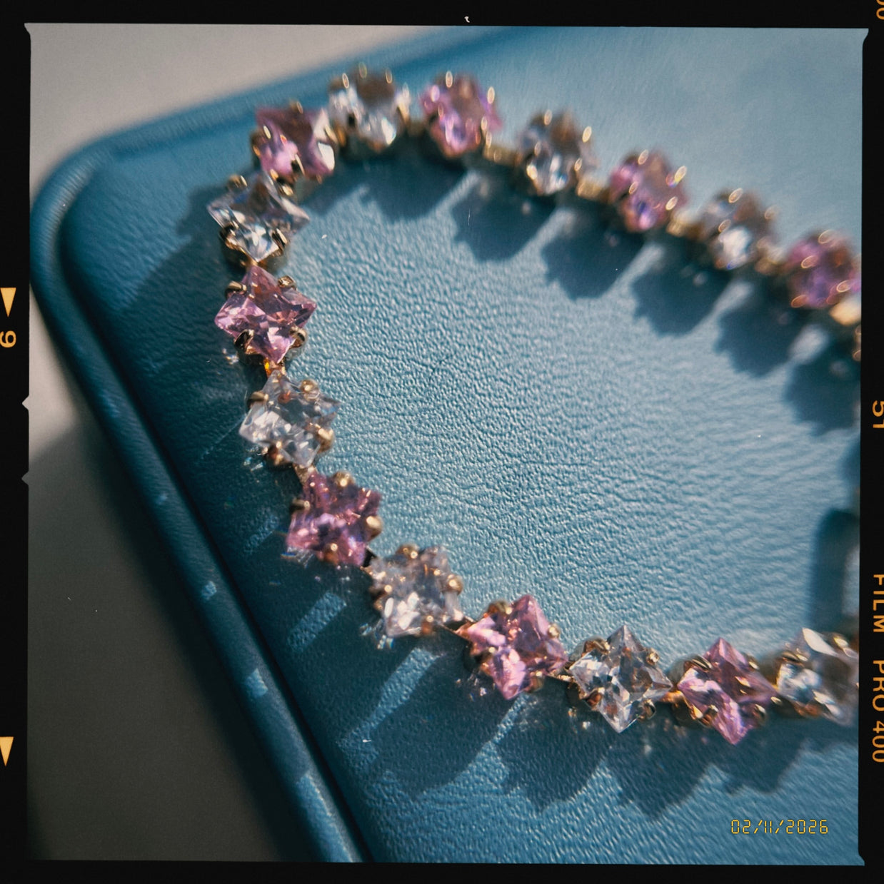 Bracelet with pink and clear gemstones on a blue textured surface