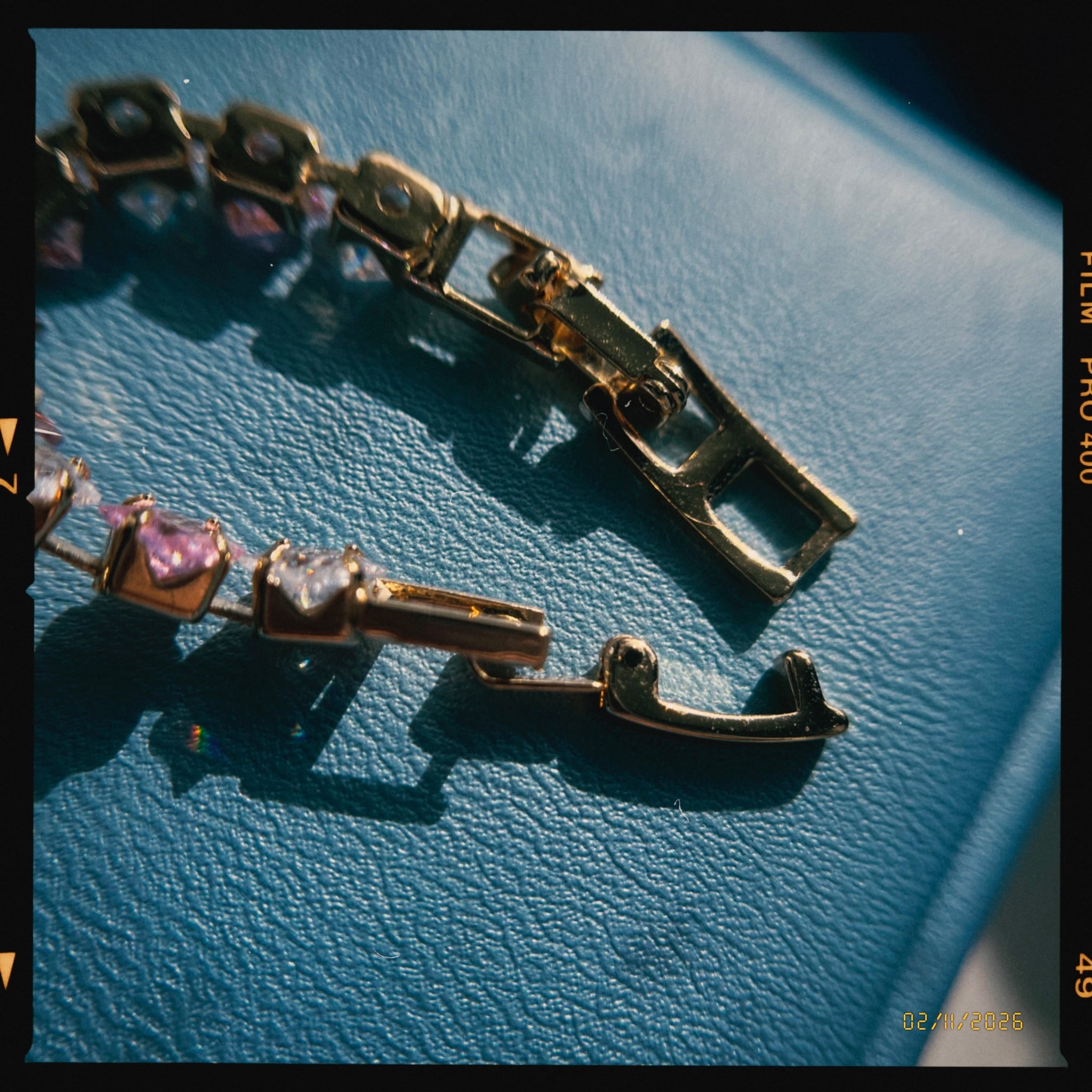 Gold bracelet with gemstones on a blue textured surface