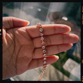 Hand holding a delicate bracelet with small stones against a blurred background