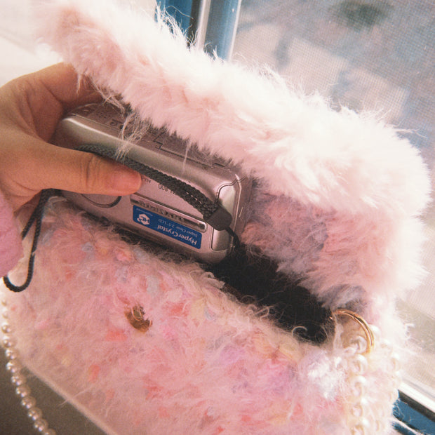 Someday she - Deleted Scenes one-of-a-kind hand-blended artisanal crochet shaggy bag in soft pink, with a vintage digital camera tucked inside and a pearl strap.