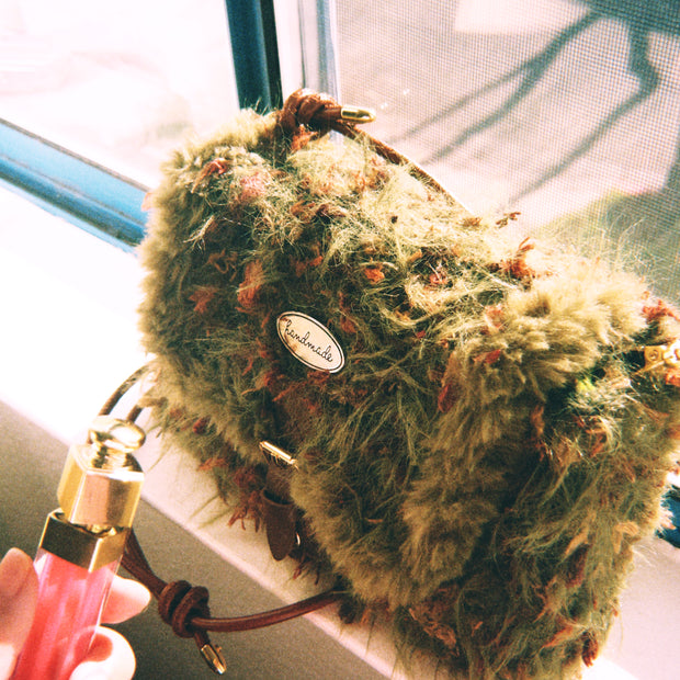 Someday she - Moss Has No Deadline one-of-a-kind hand-blended forest green artisanal bag with shaggy moss-like texture, held by a hand near a sunlit window