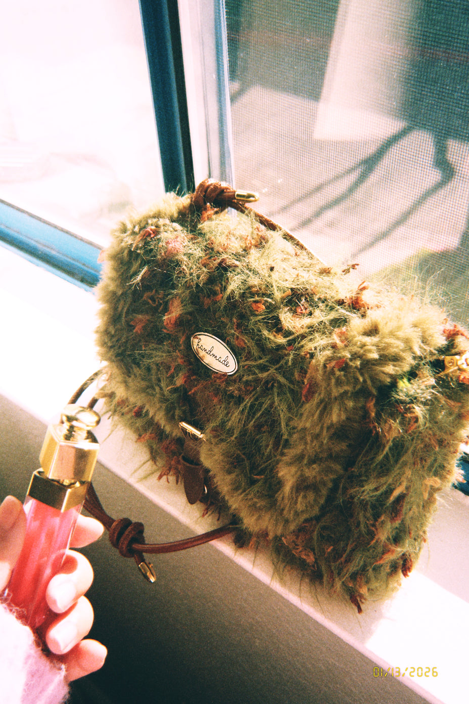 Someday she - Moss Has No Deadline one-of-a-kind hand-blended forest green artisanal bag with shaggy moss-like texture, held by a hand near a sunlit window