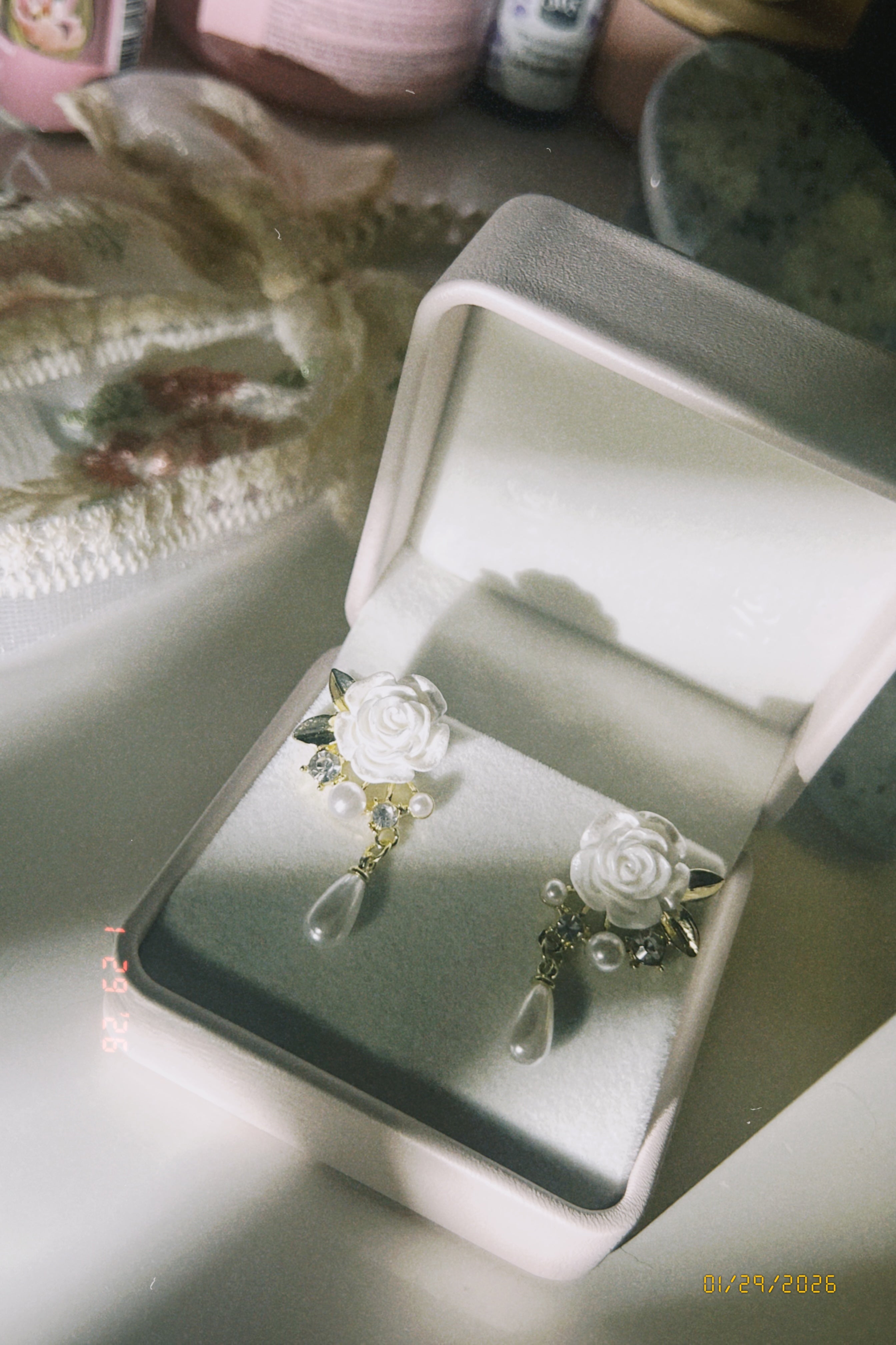 Someday she - The Dalloway vintage white rose and teardrop pearl earrings with gold accents, showcased in a classic white jewelry box with soft morning sunlight.