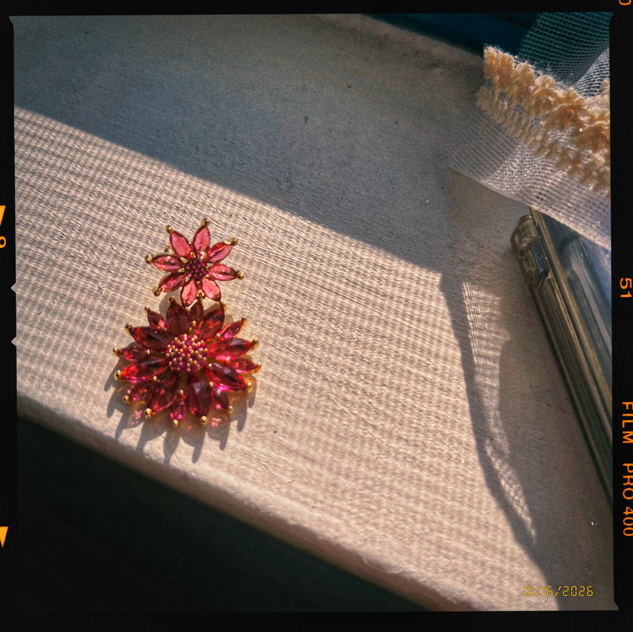 Someday she - The Pomegranate Stain vintage ruby red crystal floral earrings, showcasing intricate gold details and sparkling red gemstones in dramatic natural sunlight.